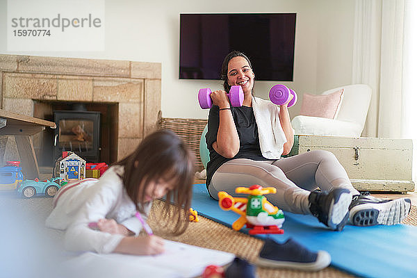 Glückliche Mutter beim Sport und Tochter beim Zeichnen beobachten