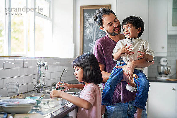Glücklicher Vater und Kinder beim Abwasch an der Küchenspüle