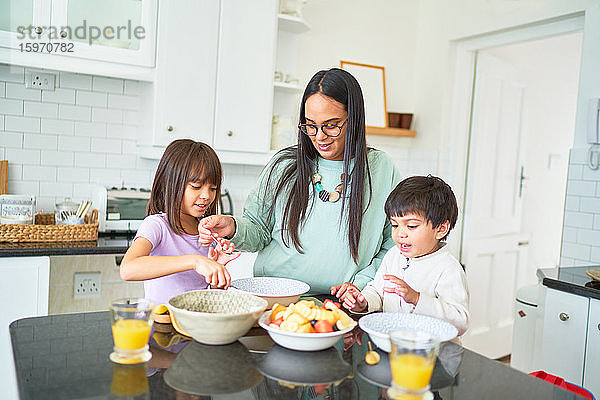 Mutter und Kinder bereiten Obst in der Küche zu