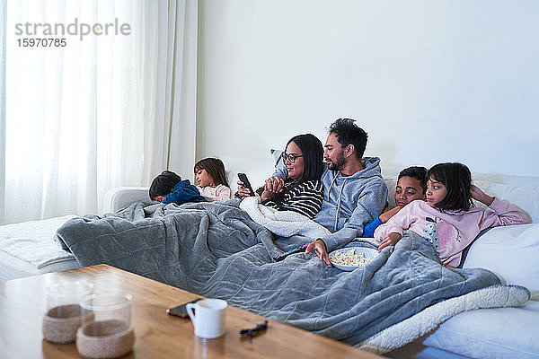 Familie entspannt sich und sieht einen Film auf dem Wohnzimmersofa