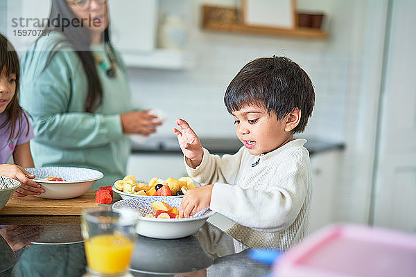 Süßer Junge isst frisches Obst in der Küche