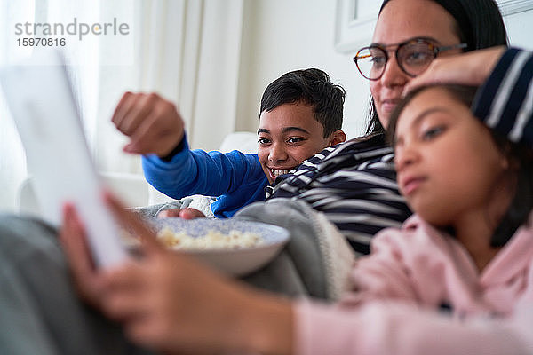Mutter und Kinder mit Popcorn sehen einen Film auf einem digitalen Tablet