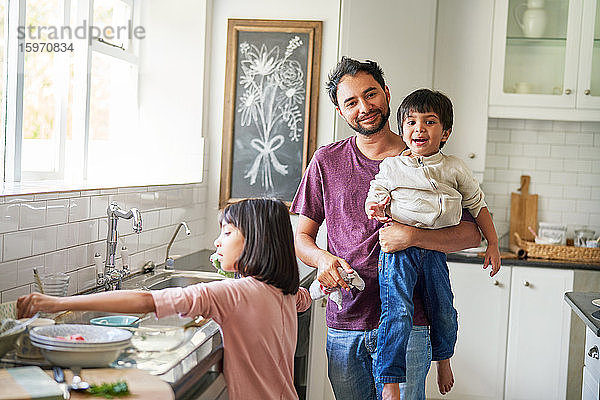 Portrait glücklicher Vater und Kinder beim Abwasch in der Küche