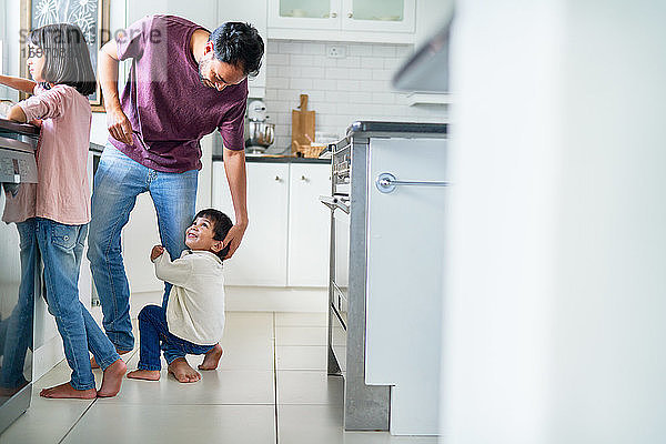 Anhänglicher Junge umarmt Bein des Vaters in der Küche