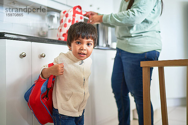 Porträt eines süßen Jungen mit Rucksack in der Küche