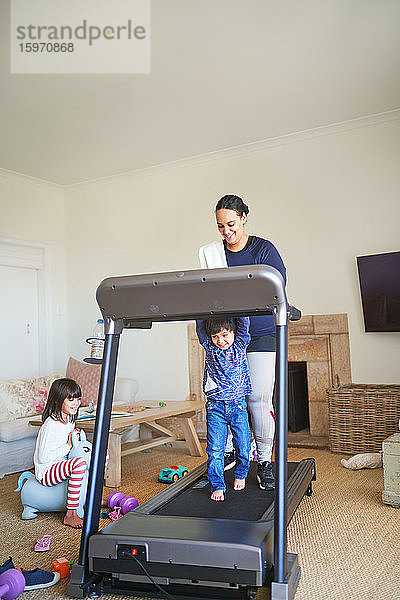 Mutter und Sohn laufen auf dem Laufband im Wohnzimmer