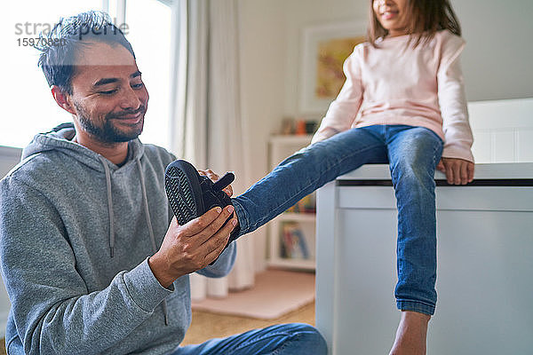 Vater hilft Tochter beim Anziehen der Schuhe