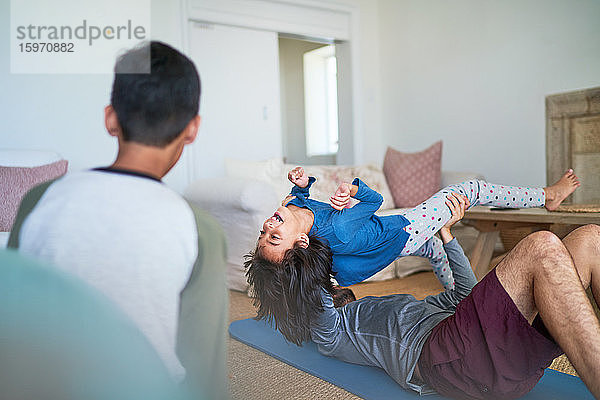 Spielerischer Vater hebt die Tochter und übt im Wohnzimmer