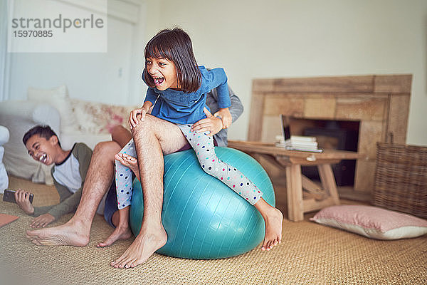 Glückliche Familie spielt im Wohnzimmer auf dem Fitnessball