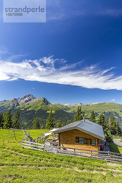 Almhütte mit Schweizer Fahne  unter herrlichen Wolken. Surses  Surselva  Graubünden  Schweiz  Europa