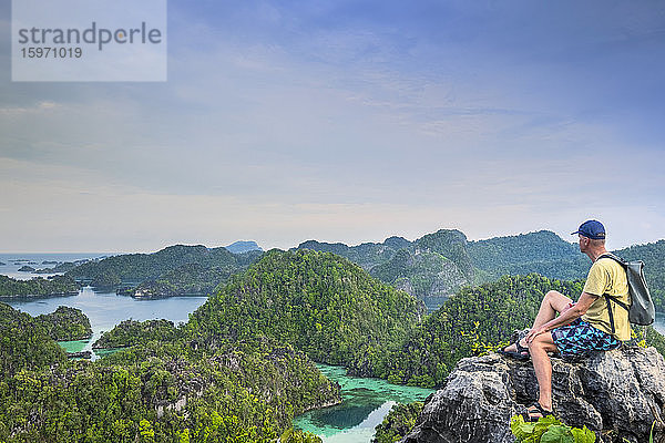 Ein Tourist  der vom Harfat-Berg aus über eine Inselbucht blickt  Gewürzinseln  West-Papua  Indonesien  Südostasien  Asien