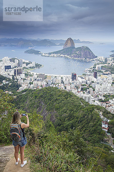 Eine Wanderin mit Blick über die Landschaft von Rio zum Zuckerhut vom Tijuca-Nationalpark  Rio de Janeiro  Brasilien  Südamerika