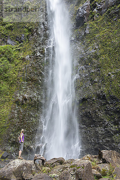 Wanderer bewundert einen Wasserfall entlang des berühmten Kalalau-Trails  entlang der Na Pali-Küste von Kauai  Kauai  Hawaii  Vereinigte Staaten von Amerika  Nordamerika
