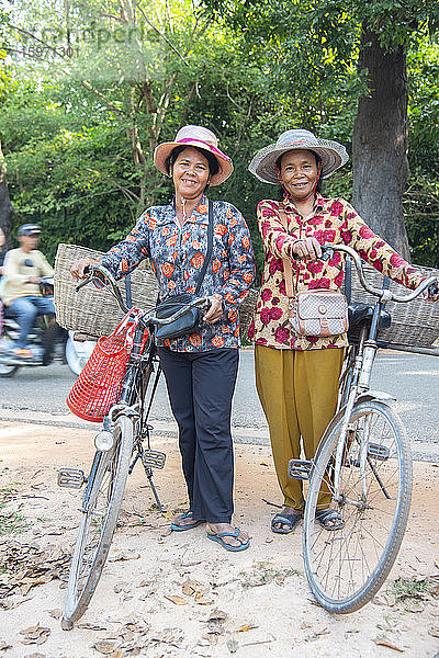 Zwei einheimische Frauen mit ihren Fahrrädern lächeln zusammen in Siem Reap  Kambodscha  Indochina  Südostasien  Asien