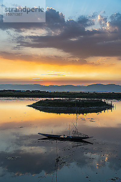 Wolken und traditionelles Ruderboot  die sich bei Sonnenuntergang im Wasser spiegeln  Inle-See  Shan-Staat  Myanmar (Burma)  Asien