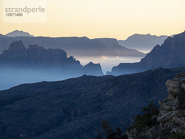 Tiefliegende Wolken füllen das Tal bei Sonnenaufgang in Sharaf Al Alamayn  Sultanat Oman  Naher Osten