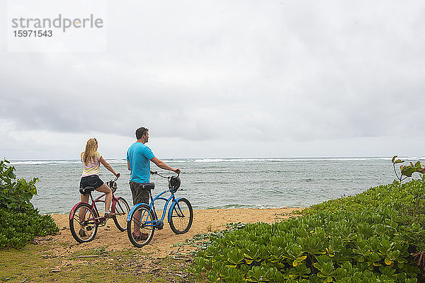 Paar mit Fahrrädern mit Blick auf den Ozean auf Kauai bei Kapaa  Hawaii  Vereinigte Staaten von Amerika  Nordamerika