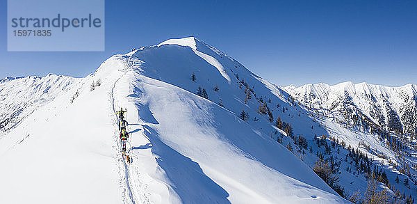 Ein Team von drei Skifahrern dringt auf den Bergrücken vor  Mount Meriggio  Valtellina  Lombardei  Italien  Europa
