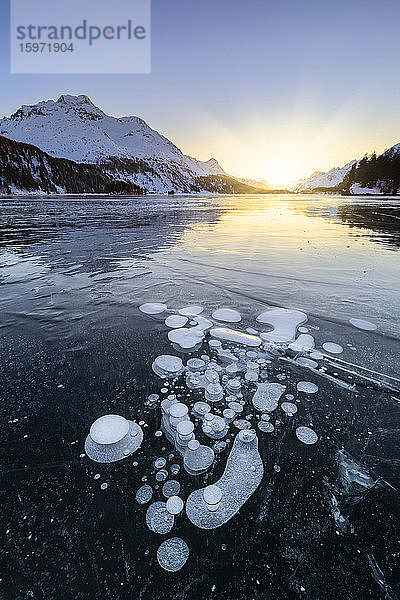Methanblasen in der eisigen Oberfläche des Silsersees mit schneebedeckter Spitze im Licht des Sonnenuntergangs  Silsersee  Engadin  Kanton Graubünden  Schweiz  Europa