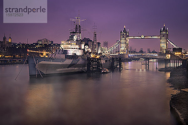 HMS Belfast mit der Tower Bridge im Hintergrund  aufgenommen am frühen Morgen mit Themse-Nebel und Stadtlichtern  London  England  Vereinigtes Königreich  Europa