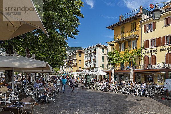 Blick auf Cafés und Besucher auf der Promenade an einem sonnigen Tag  Gardasee  Gardasee  Provinz Verona  Venetien  Italienische Seen  Italien  Europa