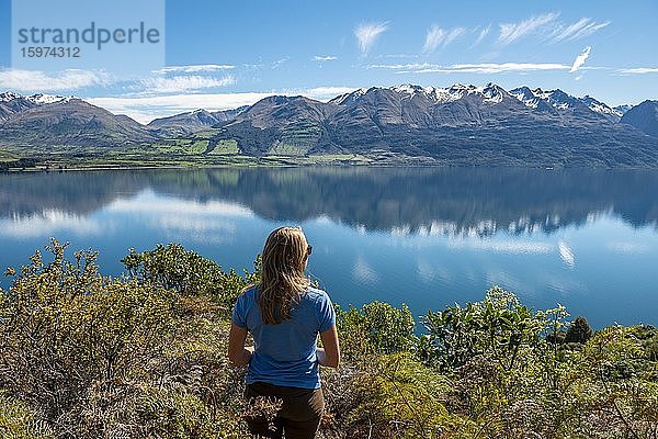 Junge Frau blickt über den See Lake Wakatipu  Berge spiegeln sich im See  Otago  Südinsel  Neuseeland  Ozeanien