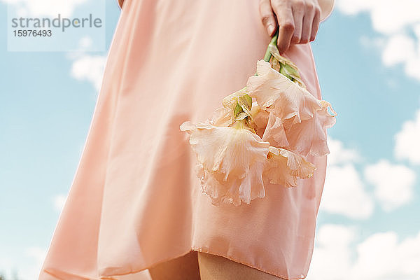 Eine Frau hält eine rosa Blume in der Hand