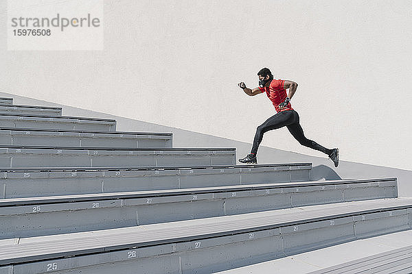 Sportler mit Gesichtsmaske läuft eine Treppe hinauf