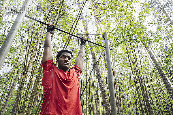Sportler beim Training am Reck im Wald