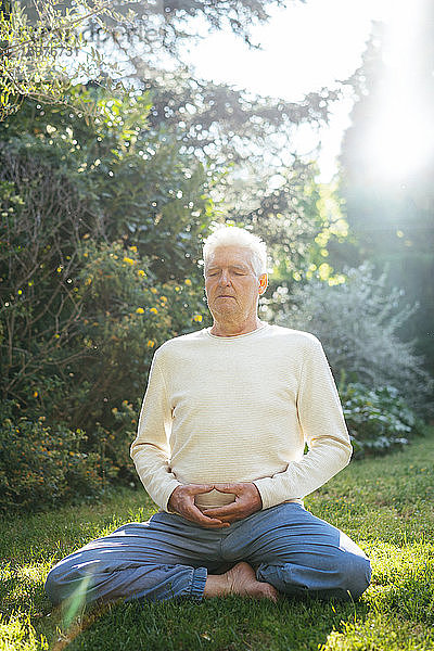 Älterer Mann meditiert im Garten
