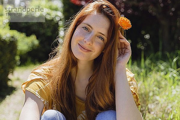 Porträt einer lächelnden jungen Frau mit Blume im Haar