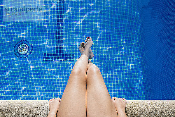 Junge Frau mit Füßen im Wasser entspannt am Pool