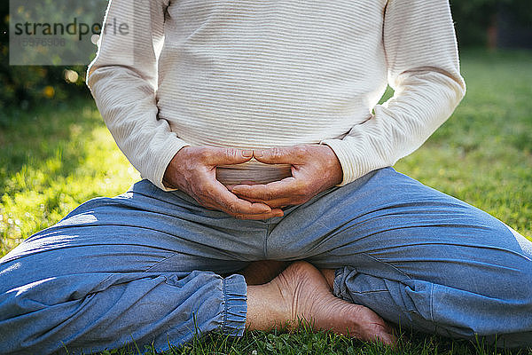 Tiefschnitt eines älteren Mannes beim Meditieren im Garten