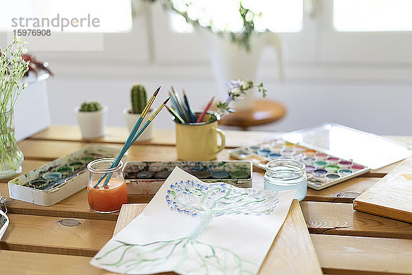 Aquarellfarben mit Zeichnung und Pinseln auf Holztisch zu Hause
