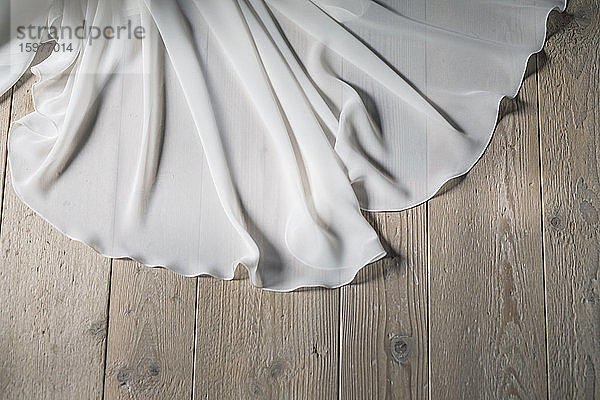 Detail eines Hochzeitskleides auf Holzboden