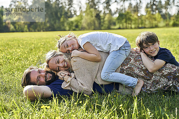 Lächelnde Familie im Gras liegend an einem sonnigen Tag