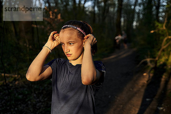 Mädchen schaut weg und trägt ein Stirnband im Wald