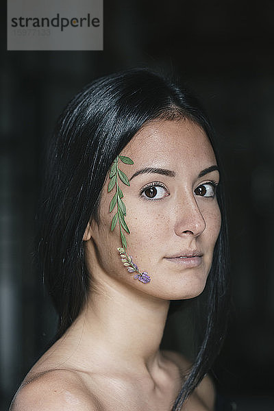 Schöne junge Frau mit Blättern im Gesicht