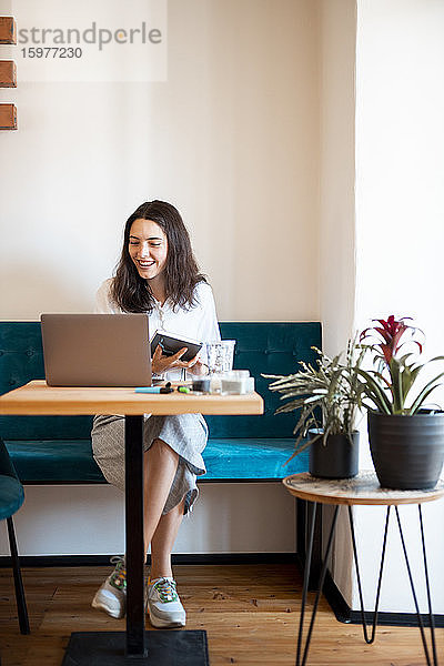 Porträt einer lächelnden jungen Frau  die zu Hause im Büro arbeitet