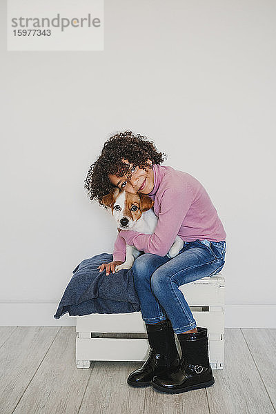 Porträt eines lächelnden kleinen Mädchens  das seinen Hund knuddelt