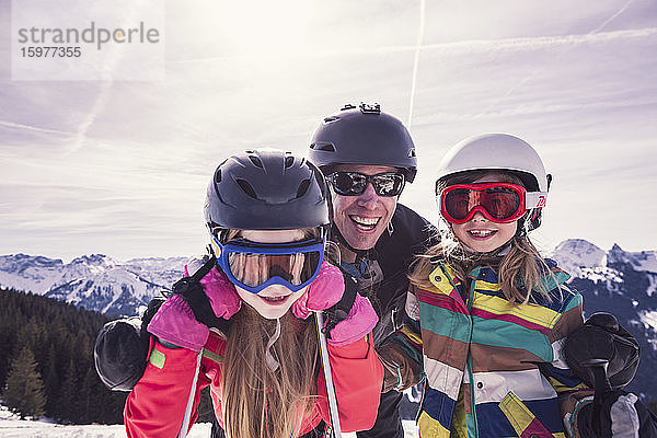 Glücklicher Vater umarmt seine Töchter beim Skiurlaub am Spitzingsee  Bayern  Deutschland