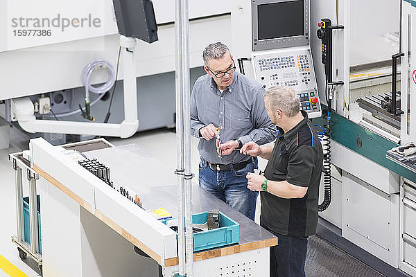 Zwei Männer unterhalten sich an einer Maschine in einer Fabrik