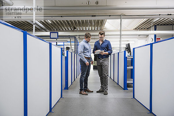 Zwei Männer mit Tablet im Gespräch in einer Fabrik