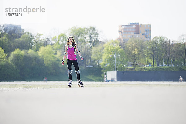 Junge Frau auf Inline-Skates in einem Park an einem sonnigen Tag