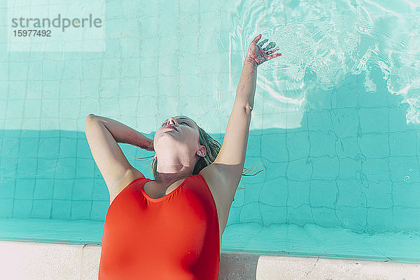 Frau im roten Badeanzug am Pool liegend