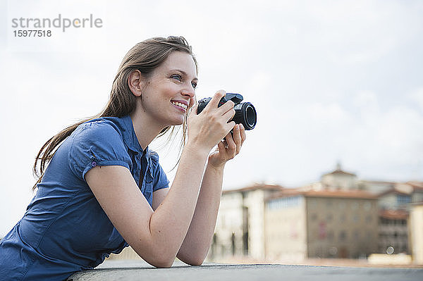 Porträt einer glücklichen Frau  die mit einer Digitalkamera Fotos macht  Florenz  Italien