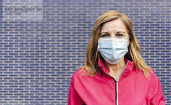 Frau mit chirurgischer Maske vor einer blauen Wand