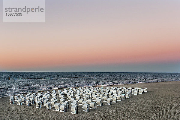 Kapuzenstühle am Strand gegen den Himmel bei Sonnenuntergang  Rügen  Deutschland