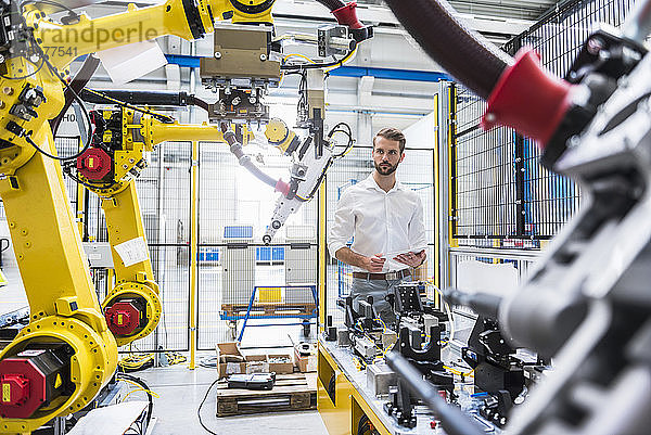 Selbstbewusster Robotikexperte bei der Betrachtung von Maschinen in einer Produktionsstätte