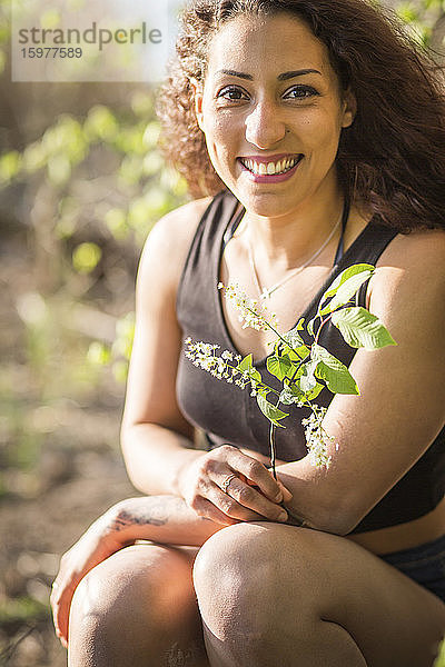 Porträt einer glücklichen jungen Frau mit Zweig in der Natur